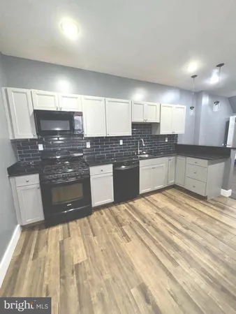 a large kitchen with stainless steel appliances kitchen island granite countertop a sink and cabinets