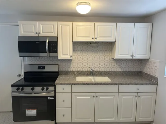 a kitchen with white cabinets and a stove top oven