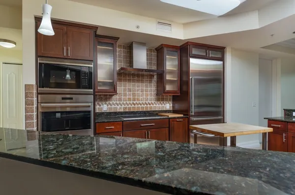 a kitchen with stainless steel appliances kitchen island granite countertop a stove and cabinets