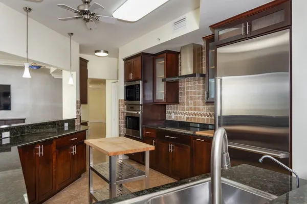 a kitchen with stainless steel appliances granite countertop a refrigerator and a stove