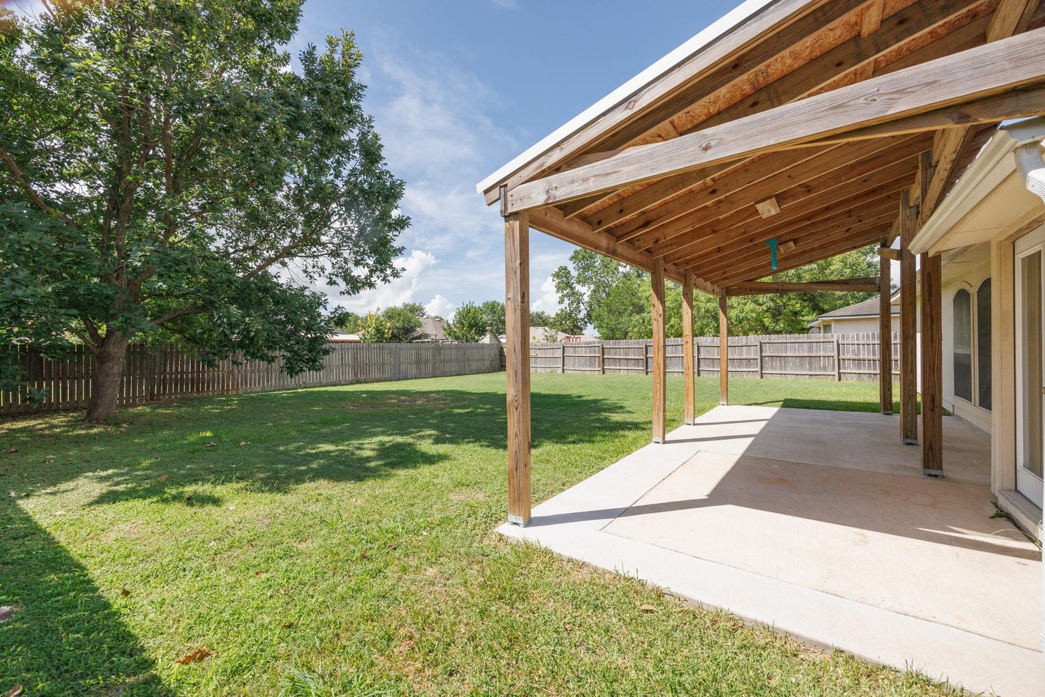 521 Britni Loop Kyle, TX 78640 - Photo 2 of 23 a view of a backyard with wooden fence and a large tree