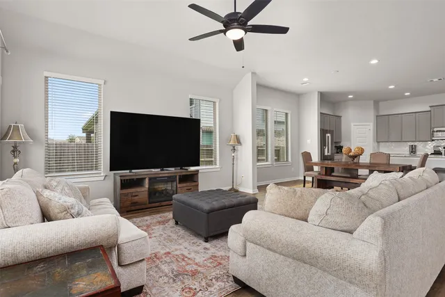 a living room with furniture kitchen view and a wooden floor