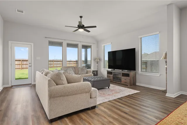 a living room with furniture flat screen tv and a large window