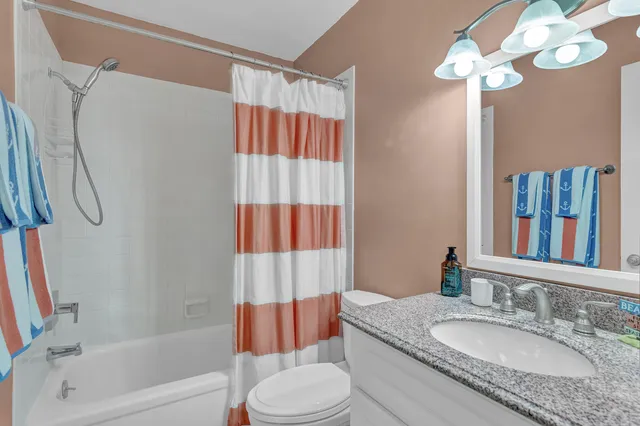a bathroom with a granite countertop bathtub sink vanity mirror and toilet