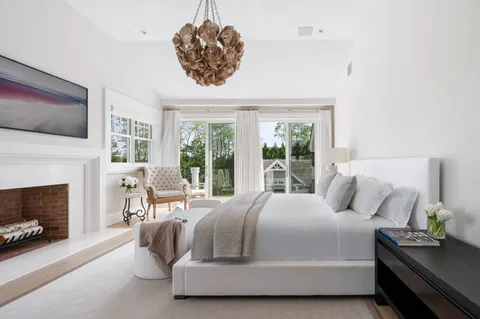 a bedroom with a bed a flat screen tv and a fireplace