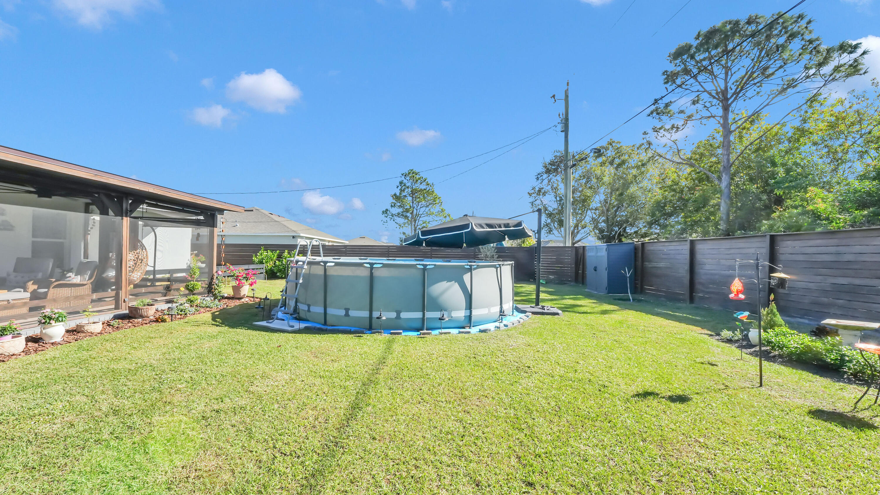1382 Southwest Becker Road Port St. Lucie, FL 34953 - Photo 41 of 56 a view of a backyard with table and chairs potted plants and wooden fence