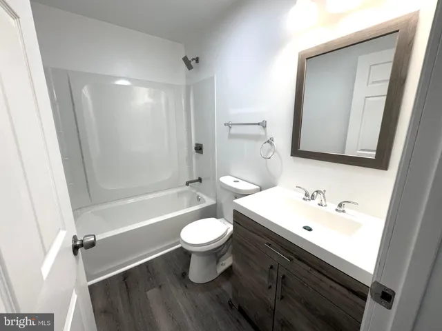 an empty room with wooden floor fireplace and windows