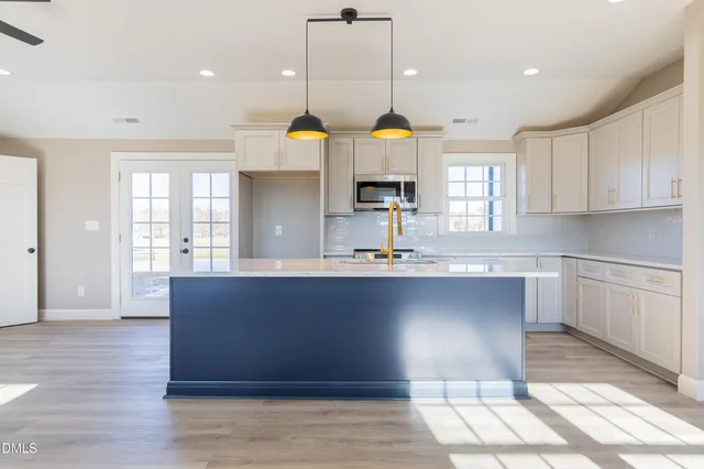 a kitchen with stainless steel appliances granite countertop a sink a stove and a wooden floors
