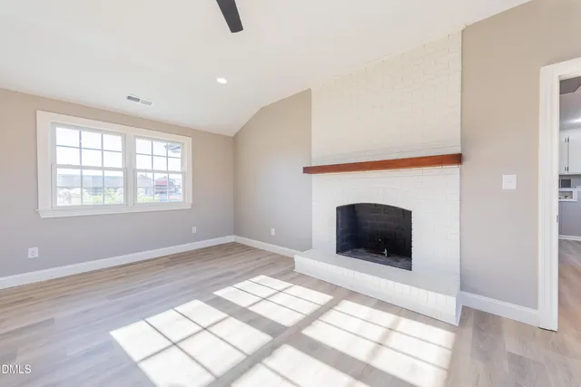 an empty room with windows and fireplace