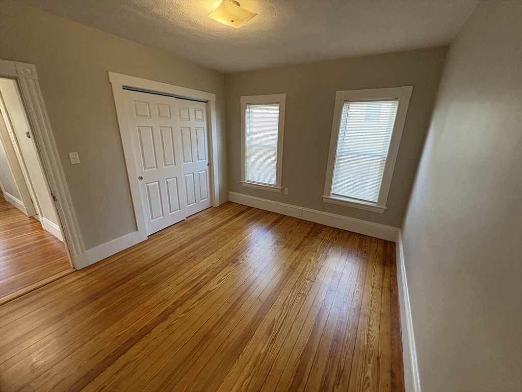 85 Swan Street, Unit 3 Everett, MA 02149 - Photo 6 of 9 an empty room with wooden floor and windows