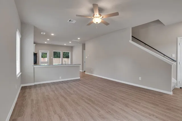 a view of an empty room with window and wooden floor