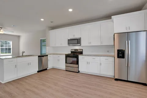 a kitchen with granite countertop white cabinets and stainless steel appliances
