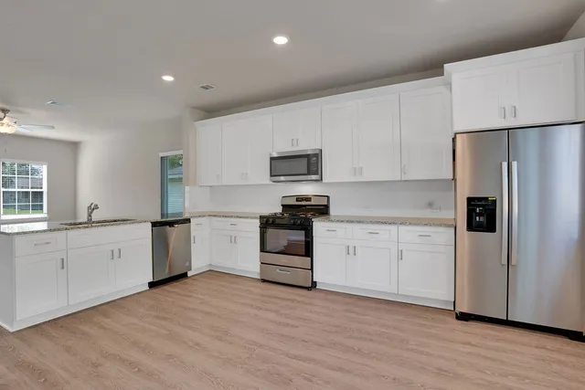 a kitchen with granite countertop white cabinets and stainless steel appliances