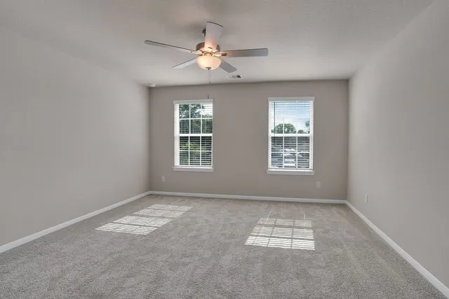 an empty room with windows and fan
