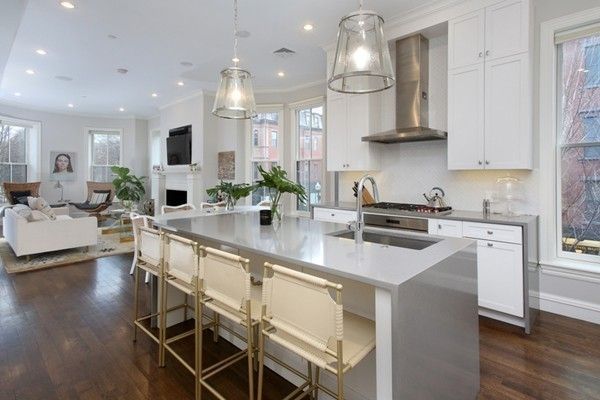 a kitchen with stainless steel appliances a sink a stove a chandelier a dining table and chairs
