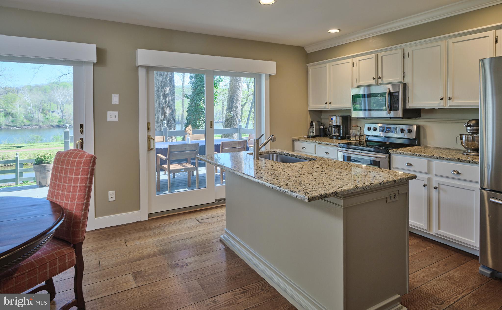 2976 River Road New Hope, PA 18938 - Photo 10 of 37 a kitchen with stainless steel appliances granite countertop a stove top oven a sink dishwasher a dining table and chairs with wooden floor