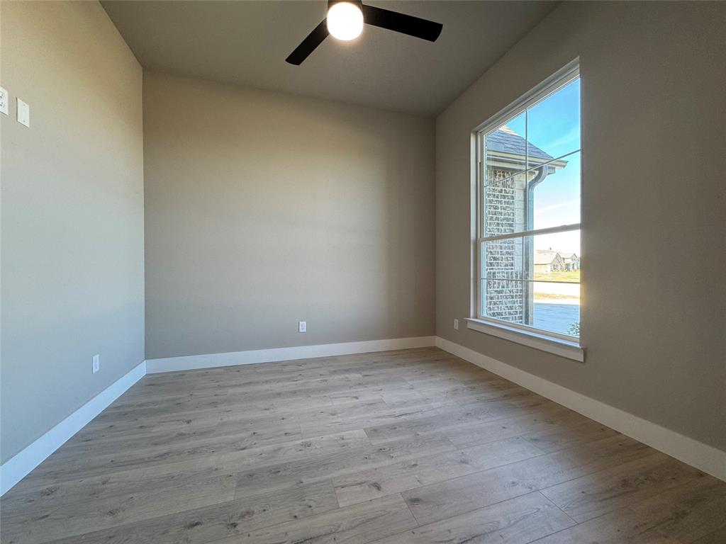 129 Mikasi Street Godley, TX 76044 - Photo 19 of 21 an empty room with wooden floor chandelier fan and windows