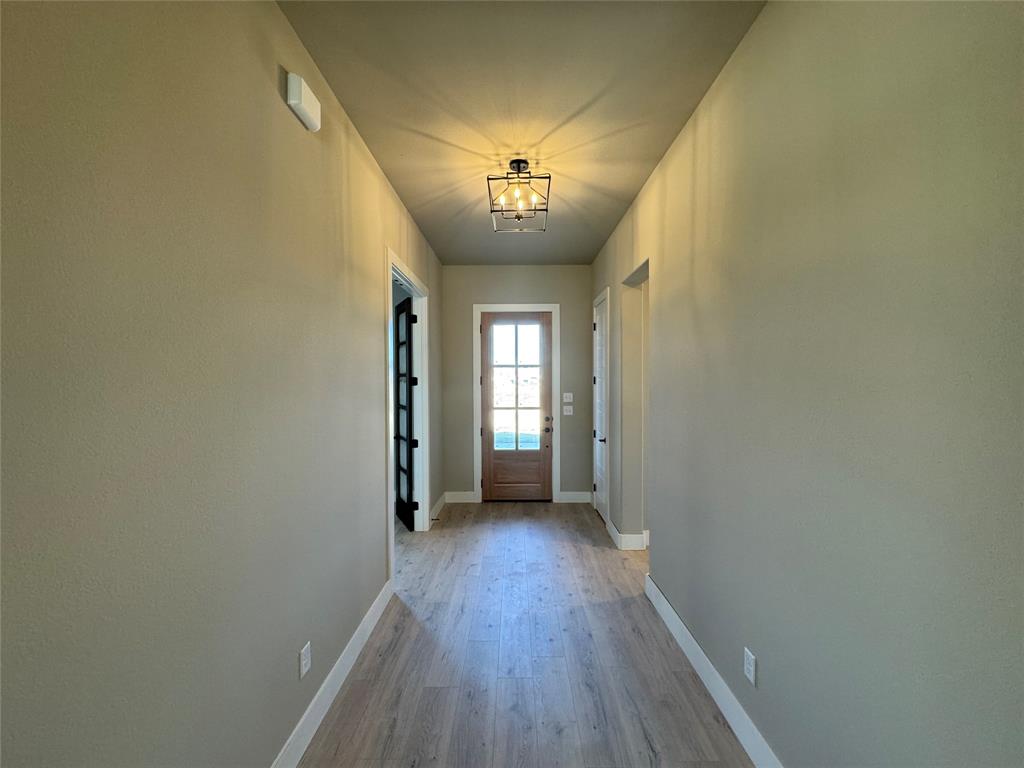 129 Mikasi Street Godley, TX 76044 - Photo 6 of 21 a view of a hallway with wooden floor and a chandelier