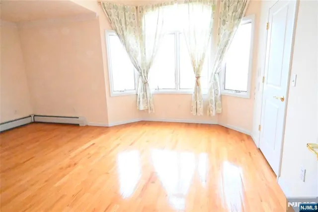 a view of empty room with window and wooden floor