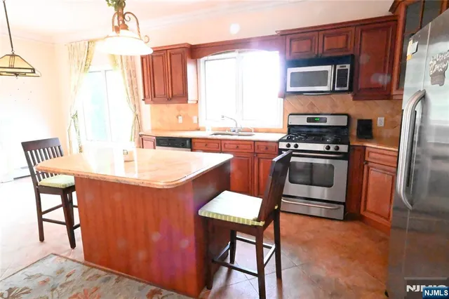 a kitchen with stainless steel appliances a sink a stove a refrigerator cabinets and dining table