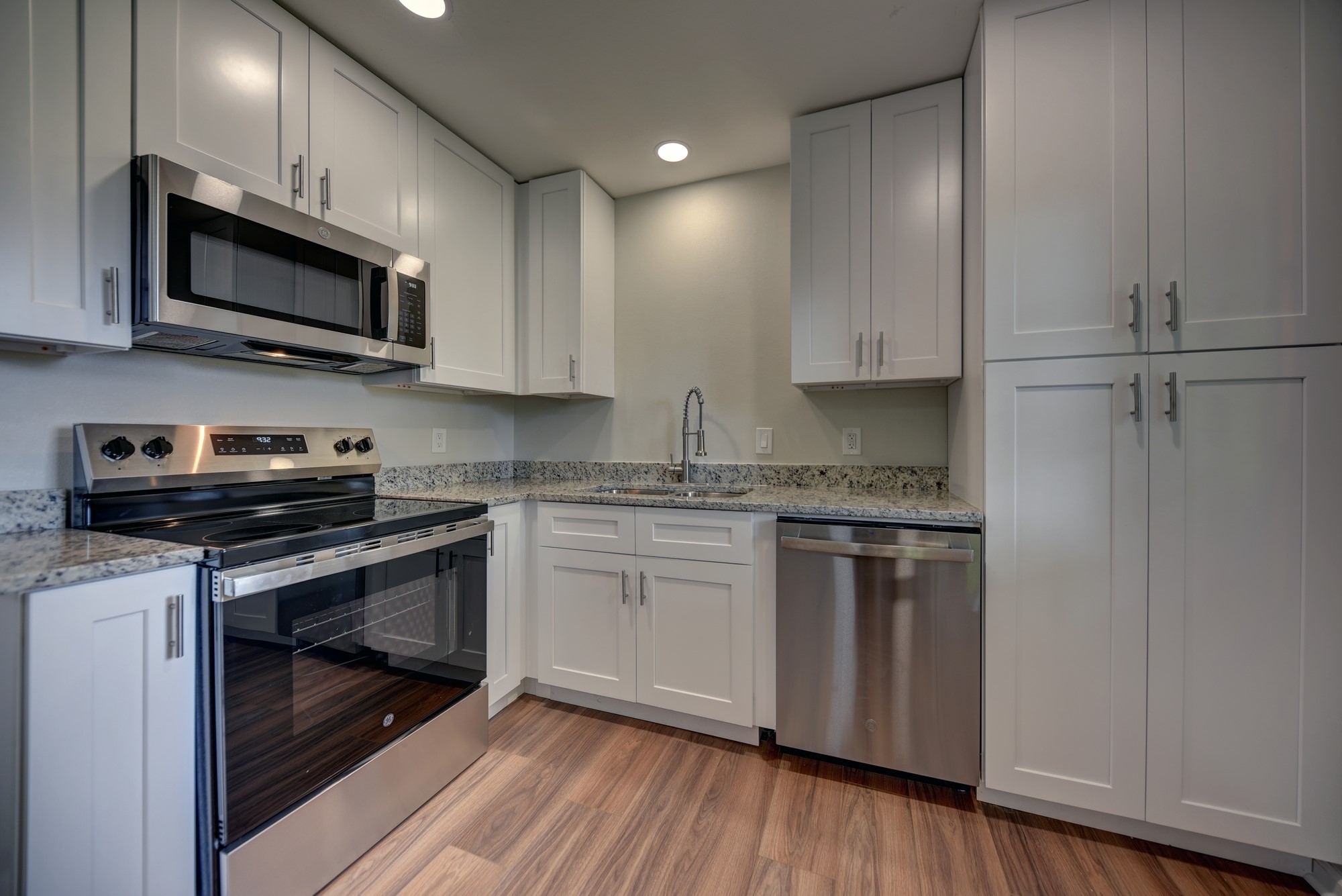 a kitchen with stainless steel appliances granite countertop a stove a sink and a microwave