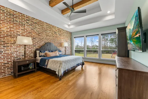 a spacious bedroom with a bed and a flat tv screen on dresser