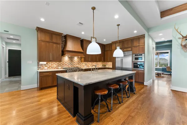 a kitchen with stainless steel appliances granite countertop wooden floors stove and white cabinets