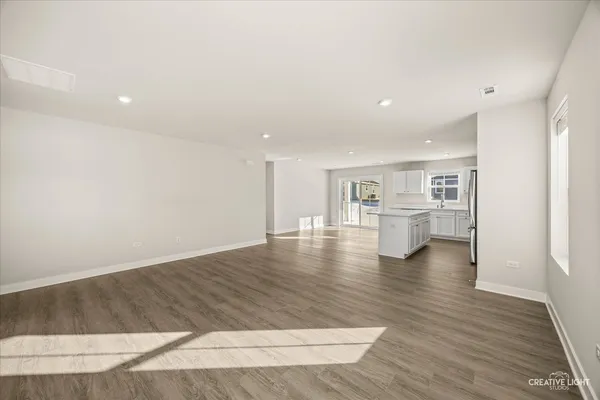 a kitchen with stainless steel appliances granite countertop a refrigerator a sink dishwasher and white cabinets with wooden floor