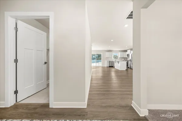 a view of a hallway with wooden floor and a bathroom