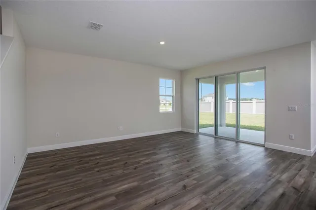 a view of an empty room with wooden floor and window