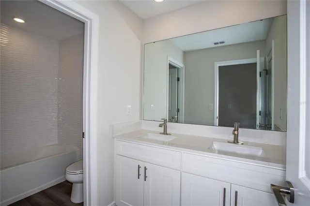 a bathroom with a double vanity sink toilet and a mirror