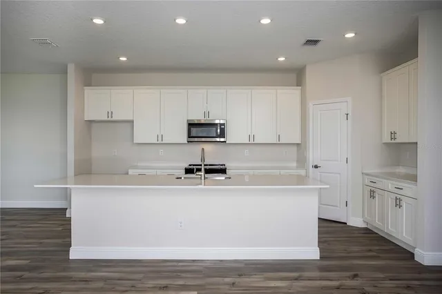 a kitchen with stainless steel appliances granite countertop a sink a stove a refrigerator and white cabinets