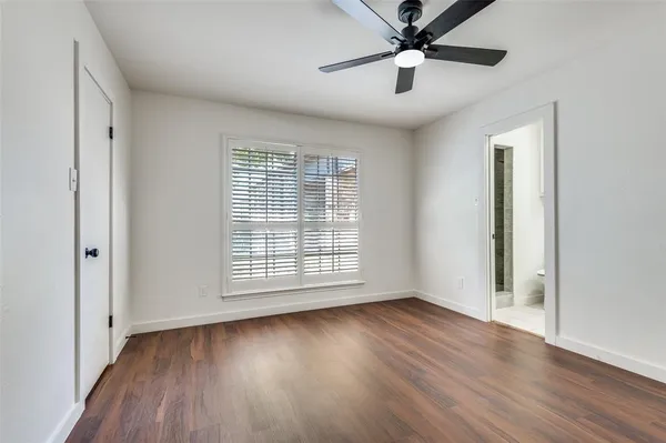 an empty room with wooden floor chandelier fan and windows