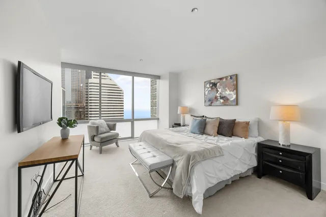 a bedroom with a bed a flat screen tv and a large window