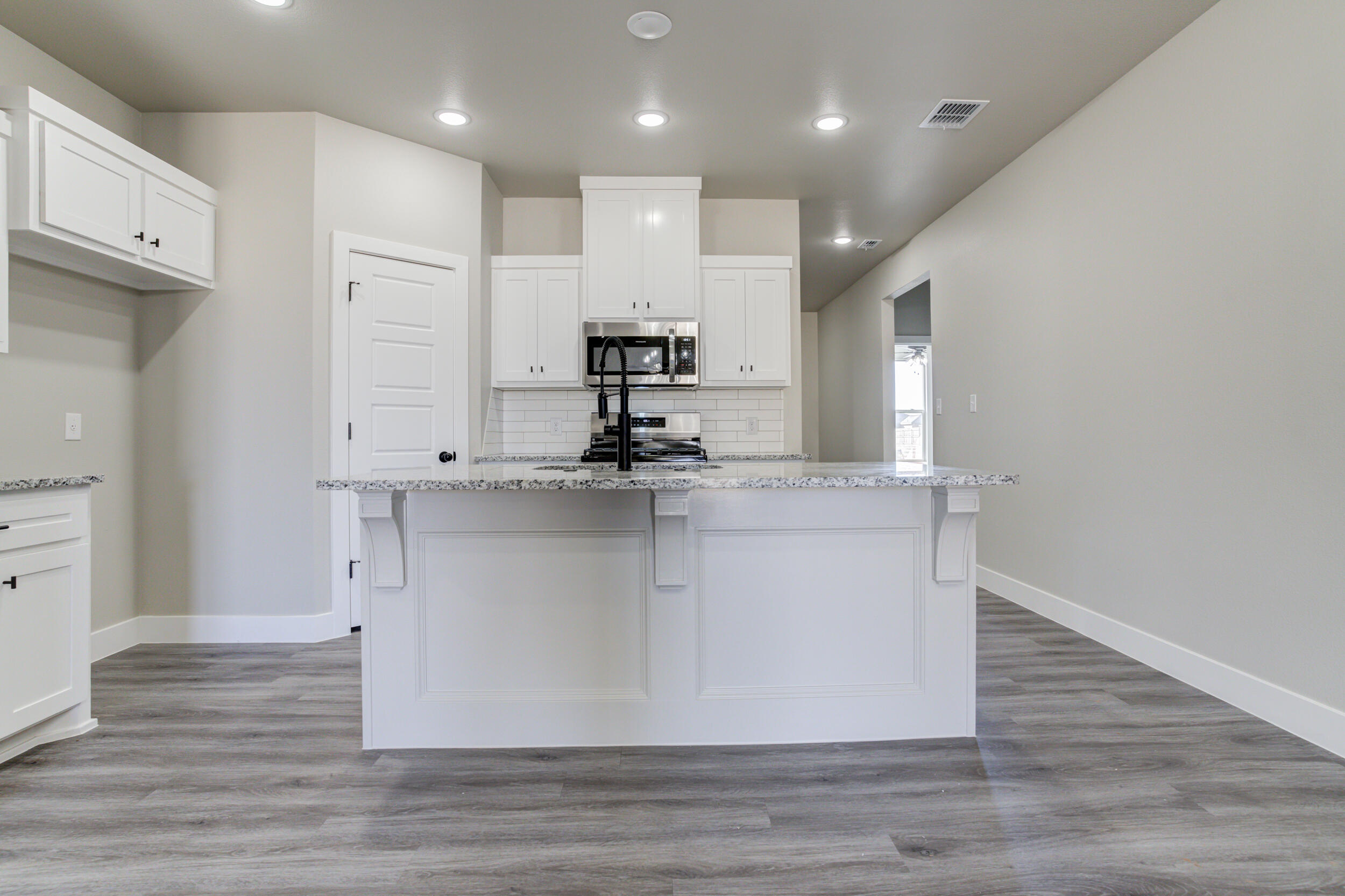6928 12th Street Lubbock, TX 79416 - Photo 12 of 50 a kitchen with kitchen island cabinets and wooden floor