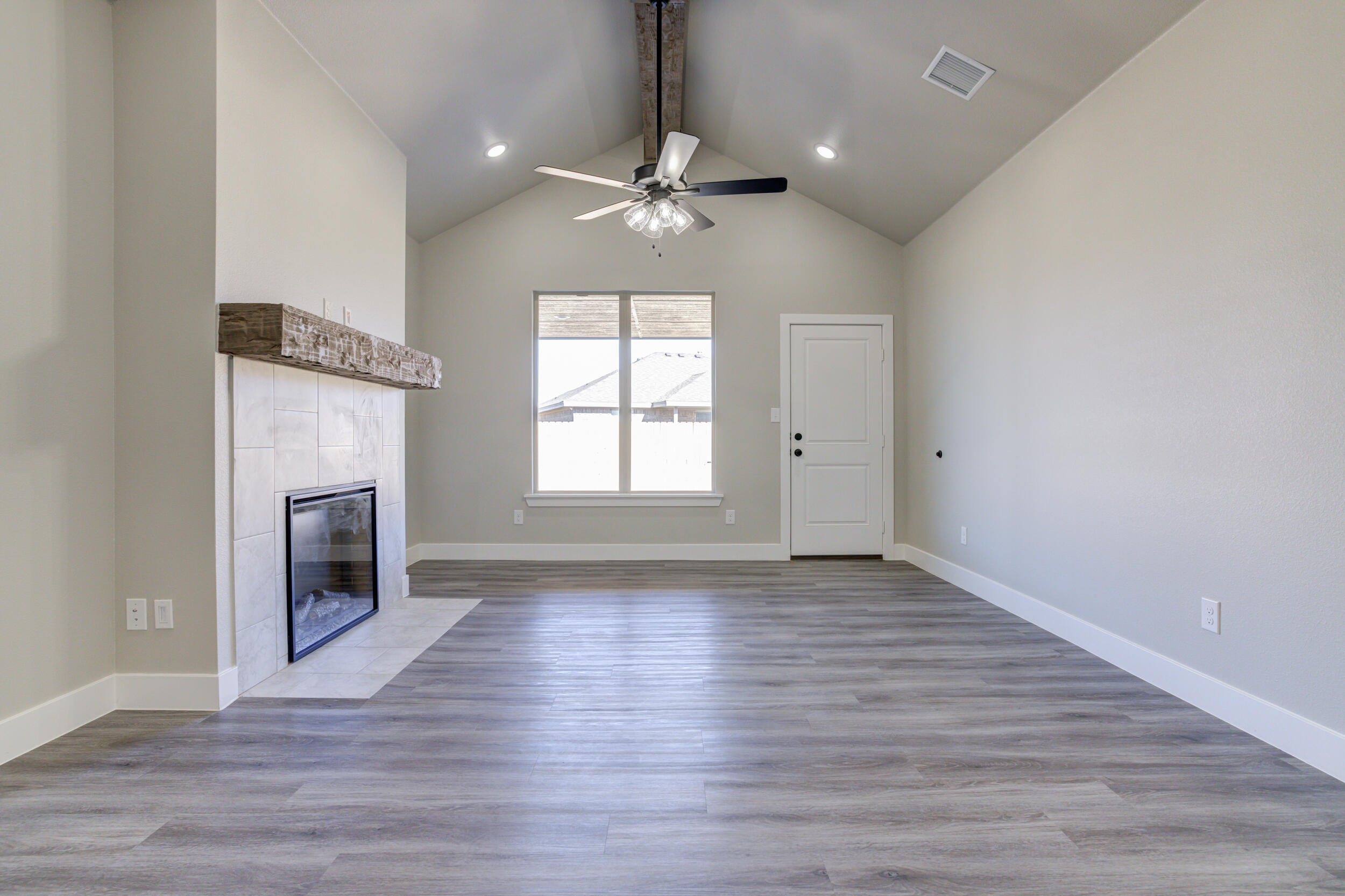 6928 12th Street Lubbock, TX 79416 - Photo 18 of 50 an empty room with wooden floor fireplace and windows