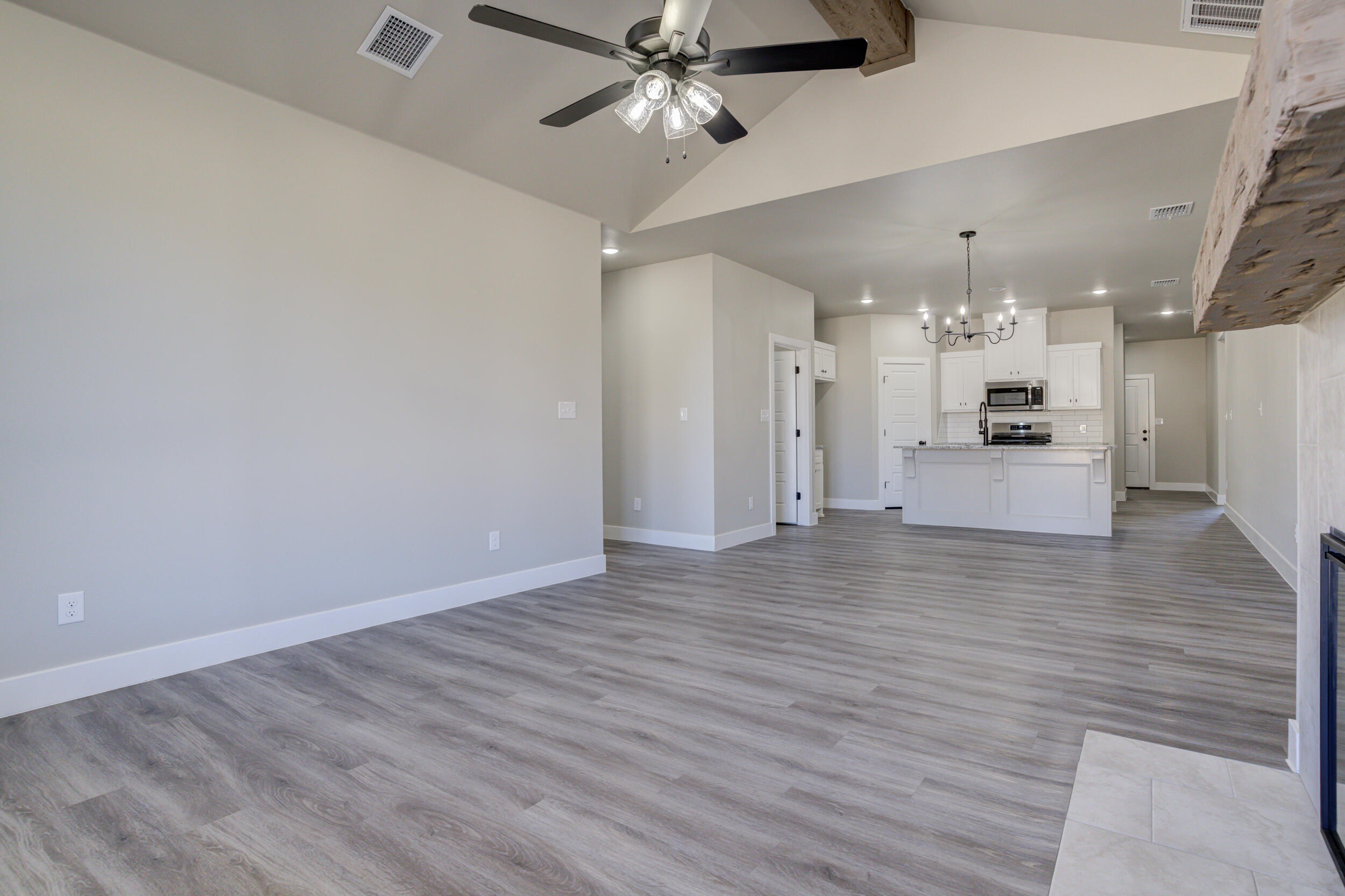 6928 12th Street Lubbock, TX 79416 - Photo 20 of 50 an empty room with wooden floor a ceiling fan a kitchen view and a ceiling fan
