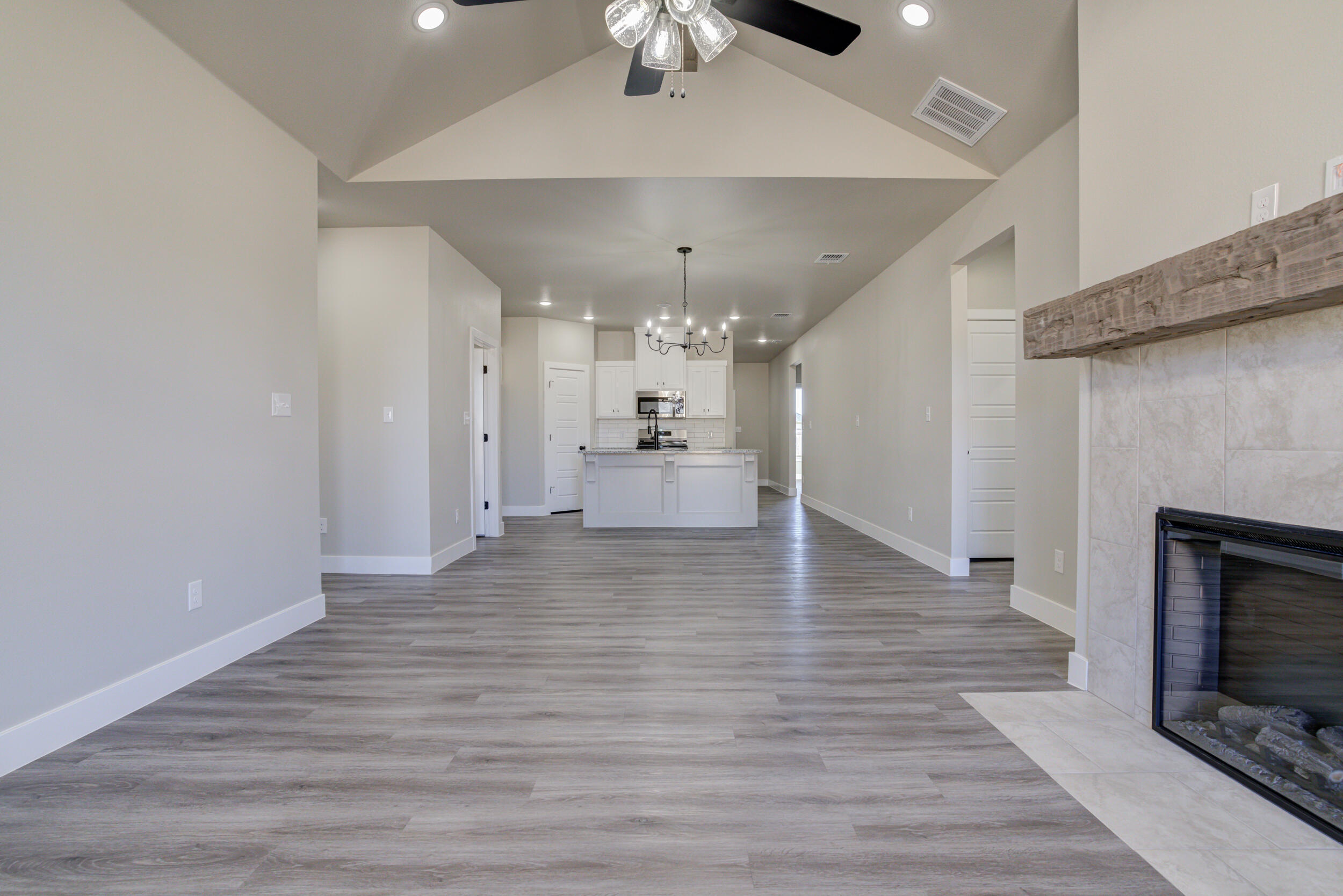 6928 12th Street Lubbock, TX 79416 - Photo 21 of 50 an empty room with wooden floor fireplace and chandelier