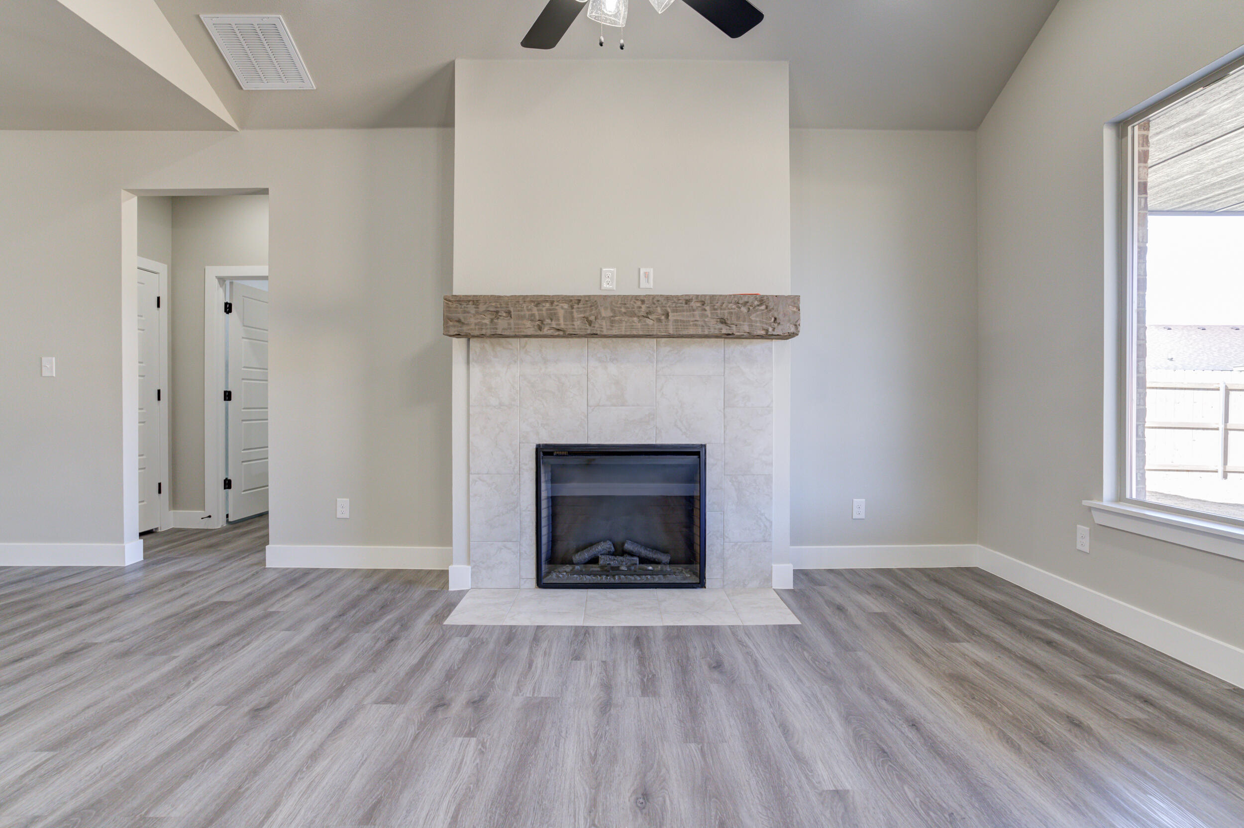 6928 12th Street Lubbock, TX 79416 - Photo 23 of 50 an empty room with wooden floor fireplace and window