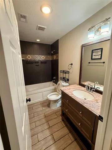 a bathroom with a granite countertop sink a toilet a mirror and shower