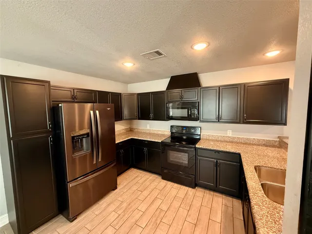 a kitchen with stainless steel appliances kitchen island granite countertop a refrigerator sink and microwave