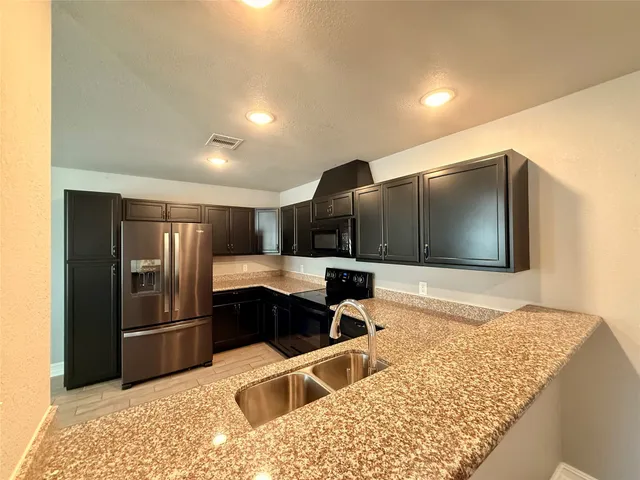 a kitchen with stainless steel appliances kitchen island granite countertop a refrigerator and a sink