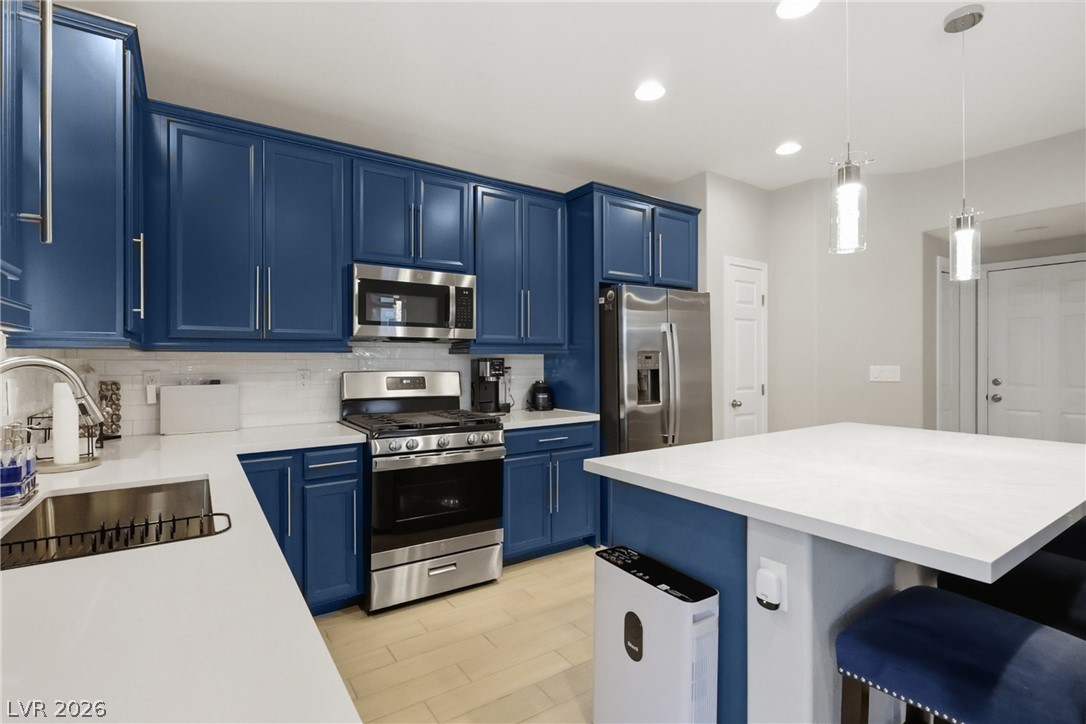 1921 Miller Ridge Avenue North Las Vegas, NV 89031 - Photo 5 of 26 This kitchen features rich blue cabinetry, sleek stainless steel appliances, and a spacious island with pendant lighting.