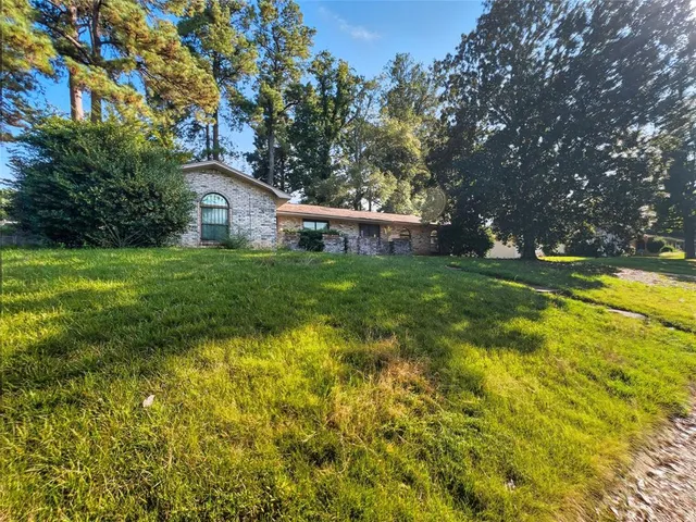 a view of a house with a big yard and large trees