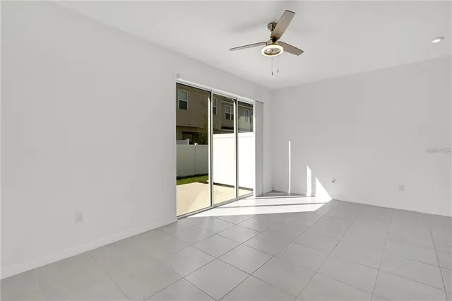 an empty room with chandelier fan and windows