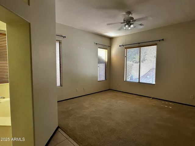 an empty room with windows and fan