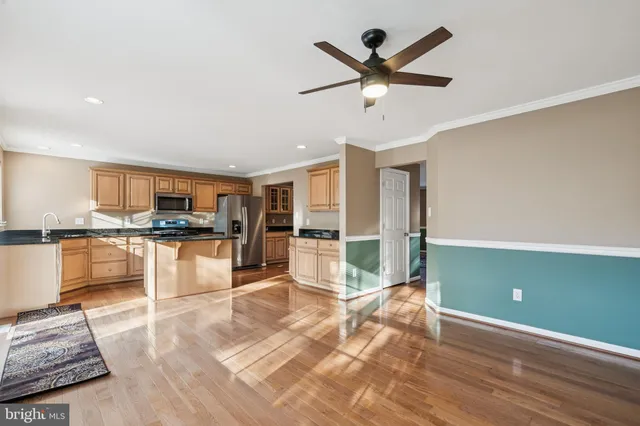 a kitchen with stainless steel appliances granite countertop a stove top oven a sink a refrigerator and white cabinets