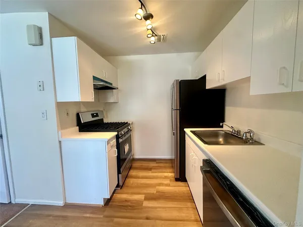 a kitchen with stainless steel appliances a stove a sink a microwave and refrigerator