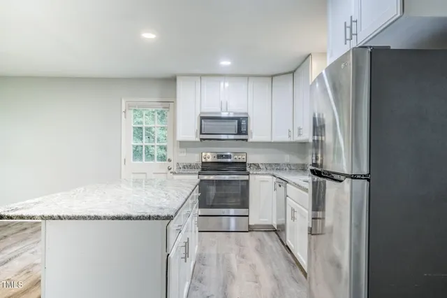 a kitchen with granite countertop a sink stainless steel appliances and window