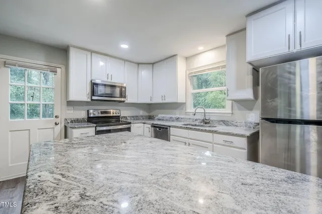 a kitchen with granite countertop a refrigerator stove and microwave